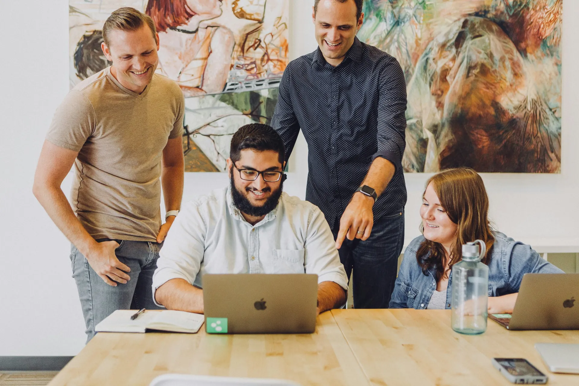 Equipe de uma pequena empresa reunida em volta de um notebook